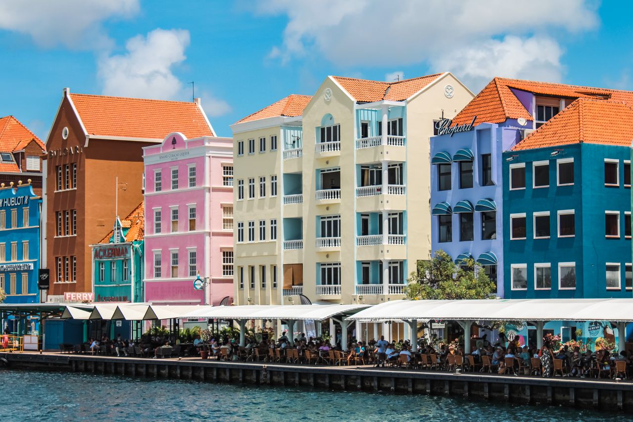 Colorful buildings line the waterfront in Willemstad, Curacao, showcasing Dutch colonial architecture.